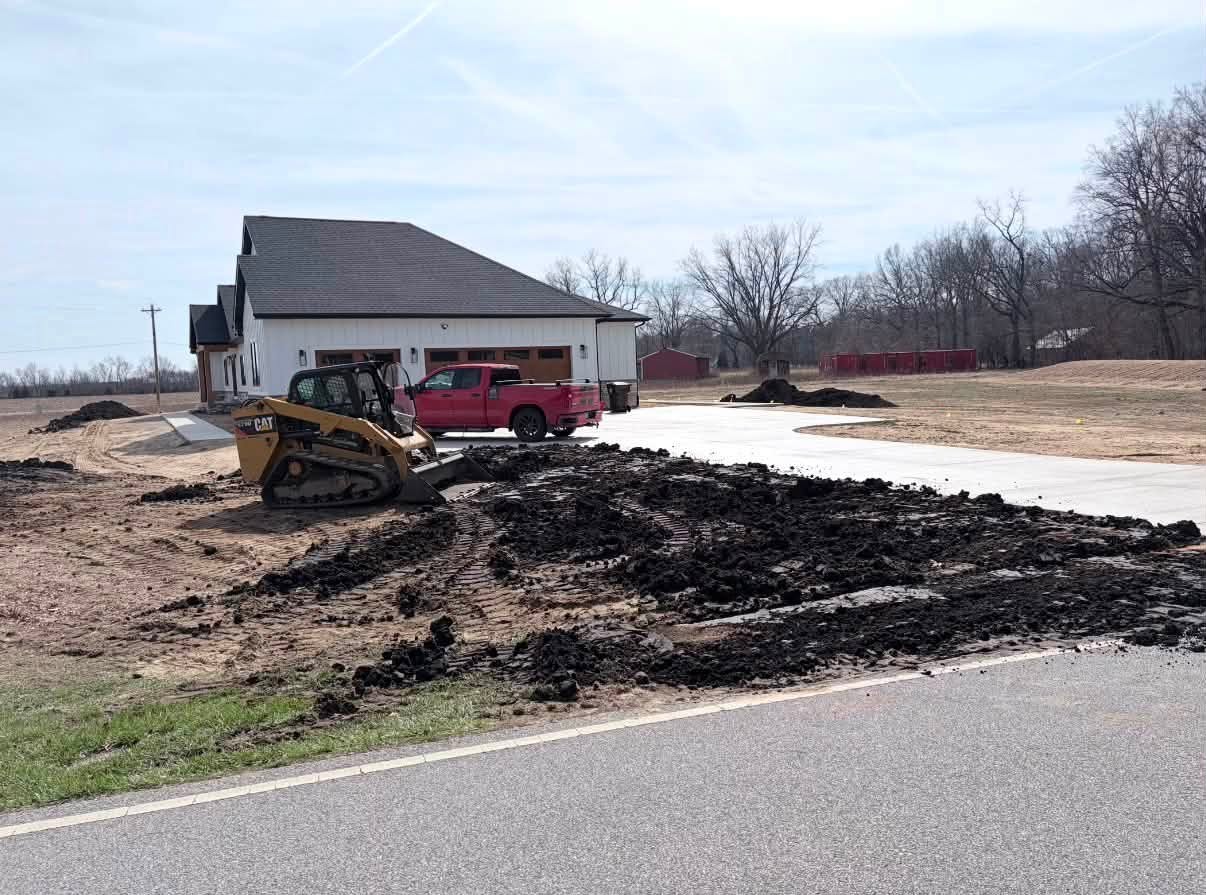 Tracked skid steer working soil beside a home